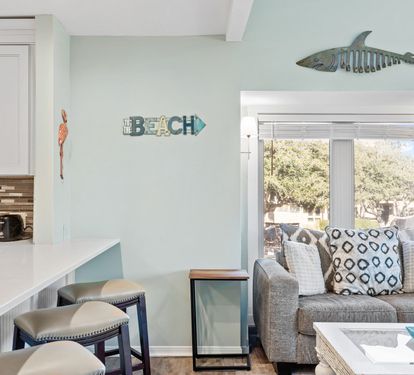 Coastal-inspired living space with comfortable seating, bar-top dining, and bright natural light creating the perfect setting to relax after a day at the beach.
