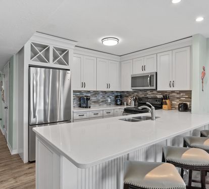 Spacious coastal kitchen with updated finishes, stainless steel appliances, and oversized bar seating — perfect for entertaining, casual dining, and relaxing after a beach day.