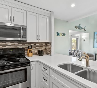 Bright and beautifully updated kitchen featuring stainless steel appliances, coastal-inspired finishes, and an open layout that flows seamlessly into the relaxing living space.