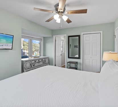 Comfortable primary bedroom with a king-size bed, coastal-inspired décor, and a peaceful atmosphere perfect for relaxing after a fun-filled day at the beach.