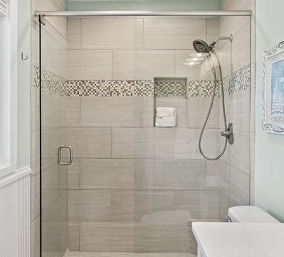 Beautifully updated primary bathroom featuring a spacious walk-in tiled shower, modern finishes, and a clean coastal design perfect for refreshing after a day at the beach.