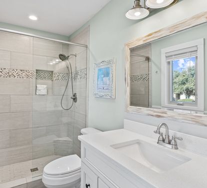 Beautifully updated primary bathroom with a spacious walk-in tiled shower, modern coastal finishes, and a bright, refreshing design perfect for relaxing after the beach.