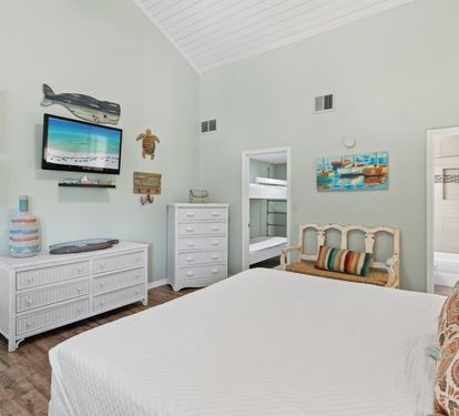 Second-floor guest bedroom featuring a king-size bed, coastal décor, vaulted ceilings, and a relaxing atmosphere perfect for family and friends to unwind after the beach.