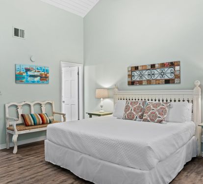 Spacious second-floor guest bedroom with a king-size bed, vaulted ceilings, coastal-inspired décor, and a relaxing retreat perfect for restful nights after beach adventures.