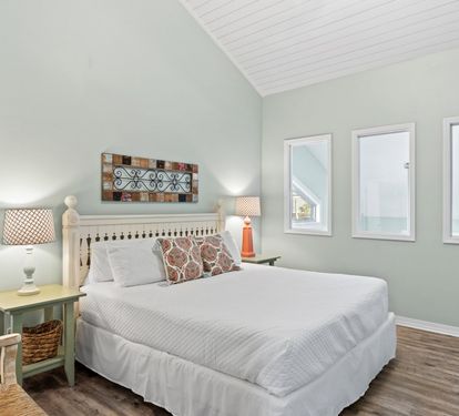 Cozy second-floor guest bedroom featuring vaulted ceilings, coastal-inspired décor, and a comfortable retreat designed for restful nights and relaxing mornings.