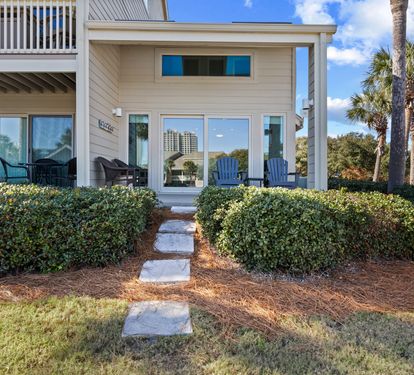 Private back patio entrance with easy access to the unit, comfortable outdoor seating, and a relaxing coastal setting perfect for enjoying the fresh air and sunshine.