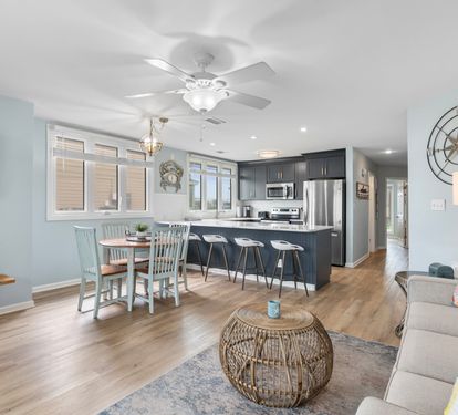 Spacious open layout with coastal charm, featuring a full kitchen, bar seating, dining table for four, and a cozy living area—perfect for relaxing and entertaining by the lake.