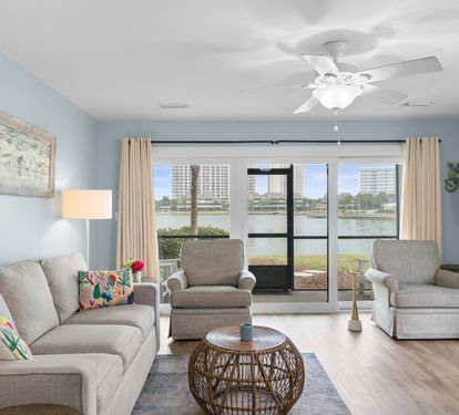 Relax in the stylish living room with lake views, plush seating, and natural light pouring through sliding glass doors that open to a screened patio.