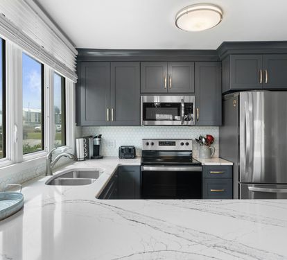 Stylish kitchen with quartz countertops, stainless steel appliances, and navy cabinetry—enjoy cooking with a view through the bright corner window.