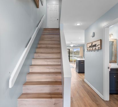 Bright entryway with coastal tones and wood flooring leads to an open living space and upstairs bedrooms—welcoming you to your beachside retreat.