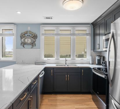 Bright and modern kitchen with sleek navy cabinets, stainless appliances, and quartz countertops—fully equipped for all your cooking needs.