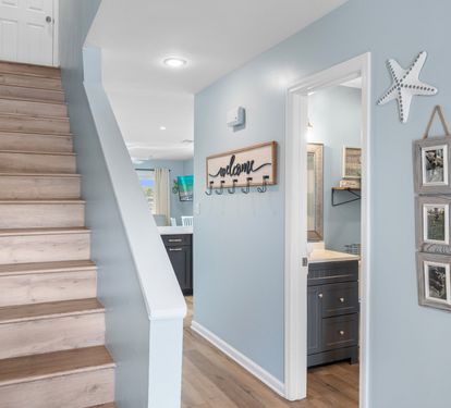 Charming entry hallway with beachy décor leads to a full bath and staircase, offering a warm welcome into this stylish coastal retreat.