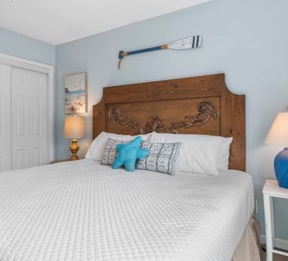 Peaceful guest bedroom with king bed, coastal accents, and crisp white bedding—designed for restful nights in a charming beachside setting.