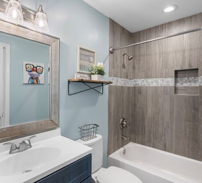 Stylish guest bathroom with a modern vanity, upgraded tile shower, mosaic accent trim, and playful coastal decor—perfect blend of comfort and charm.