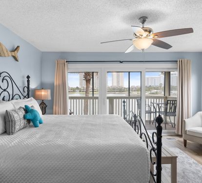 Wake up to stunning lake views in the airy primary bedroom featuring a plush king bed, soft coastal tones, and direct access to a private balcony for peaceful mornings or sunset unwinding.