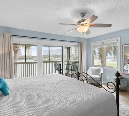 The primary bedroom boasts panoramic lake views, a king bed, cozy reading chair, and private balcony access—offering a peaceful and scenic coastal escape.