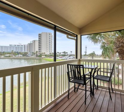 Private screened balcony with lake and Gulf views features a cozy bistro set—perfect for morning coffee, sunset drinks, or simply soaking in the coastal breeze.
