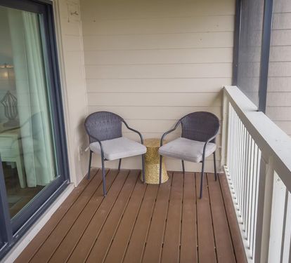 Cozy balcony nook with cushioned chairs and a side table—an ideal spot for quiet mornings, reading, or unwinding after a beach day.