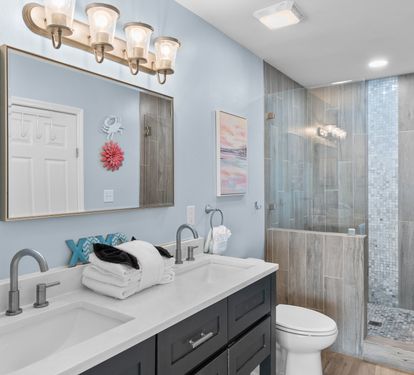 Elegant en-suite bathroom with double vanity, quartz countertop, and a spa-style walk-in shower—designed with coastal charm and modern finishes for a refreshing retreat.
