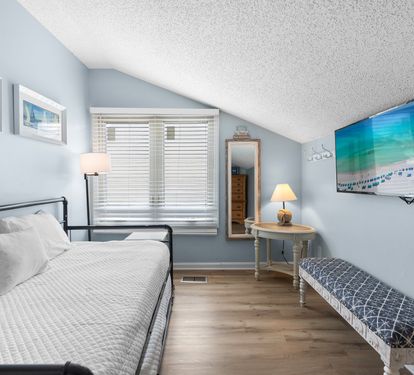 Charming upstairs guest room with a cozy daybed that converts to a king, wall-mounted TV, and stylish coastal décor—perfect for flexible sleeping arrangements.