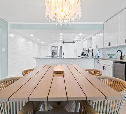 Gather around this stunning dining table where memorable meals unfold beneath elegant chandelier light in your beautiful coastal kitchen.