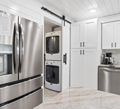 Your pristine white kitchen features stainless steel appliances and convenient laundry tucked behind sleek barn doors.