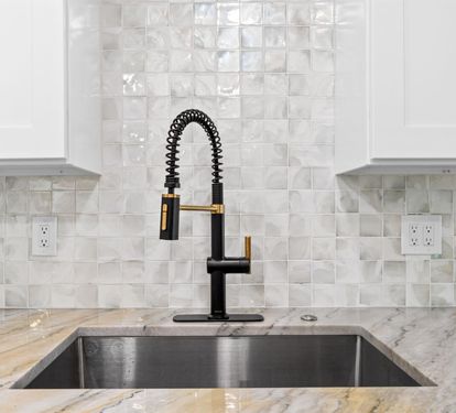 Prepare your favorite meals with this sleek kitchen featuring marble counters and modern fixtures.