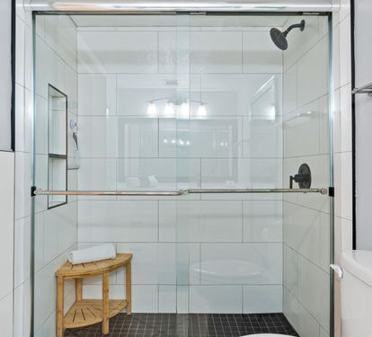 Step into your spa-like shower sanctuary with spacious glass enclosure, rainfall showerhead, and thoughtful wooden bench for ultimate relaxation.