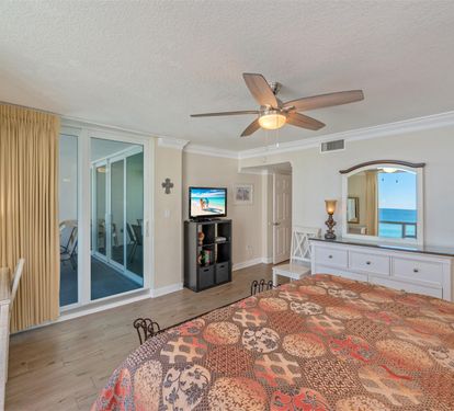 Wake up to stunning ocean views from your private balcony, while the ceiling fan keeps you cool in this bright, coastal bedroom.