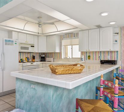 Step into your bright, fully-equipped kitchen featuring a spacious island, modern appliances, and charming turquoise accents that make cooking feel like a joy.