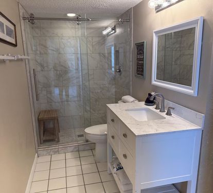 Your beautifully renovated bathroom features elegant marble shower tiles, a spacious glass-enclosed shower, and classic vanity with marble countertops for relaxing mornings.