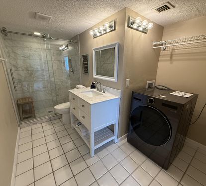 Your private bathroom combines spa-like luxury with practical convenience, featuring beautiful marble tile shower and in-suite laundry facilities.