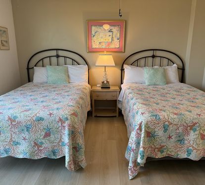Your peaceful double bedroom features vibrant tropical bedding and charming island artwork, creating a bright and comfortable retreat for restful nights.