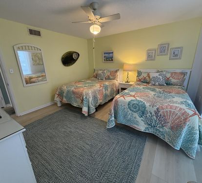 Rest peacefully in your coastal-themed bedroom featuring twin beds with vibrant coral bedding and ocean-inspired decor.