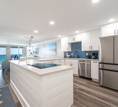 Your gourmet kitchen features sleek white cabinetry, stainless steel appliances, and a spacious island where you can cook while enjoying stunning ocean views.