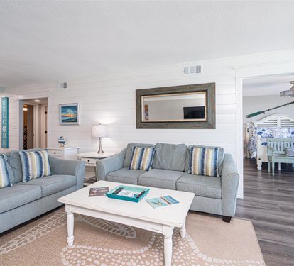 Relax in your spacious living room with comfortable seating, coastal decor, and plenty of natural light flowing throughout your vacation home.
