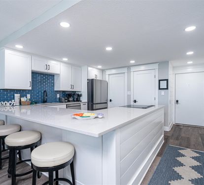 Your modern kitchen features white quartz counters, blue subway tile backsplash, and stainless appliances for effortless meal prep.