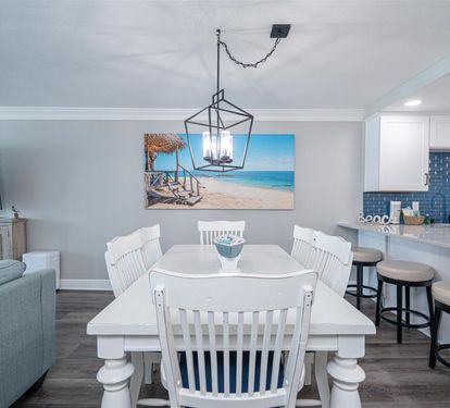 Your bright dining space features coastal charm with white furnishings and ocean artwork, perfectly connected to your modern kitchen.