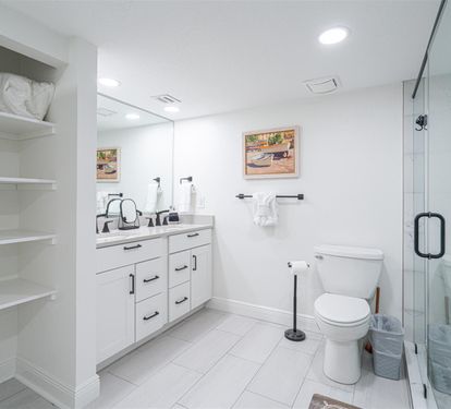 Step into your pristine private bathroom with spacious glass shower, elegant vanity, and thoughtful built-in shelving for all essentials.