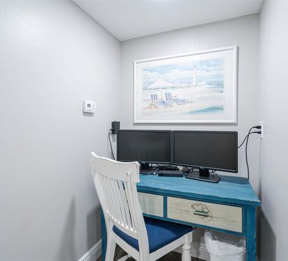 Your dedicated workspace awaits with dual monitors and a charming beach-themed desk, perfect for remote work or planning your coastal adventures.