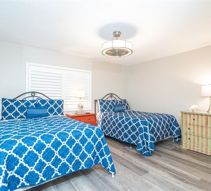 Rest peacefully in your twin bedroom featuring matching blue geometric bedding, hardwood floors, and thoughtful coastal touches.
