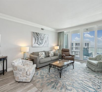 Relax in your bright coastal living room with ocean views through floor-to-ceiling windows and comfortable seating for your group.