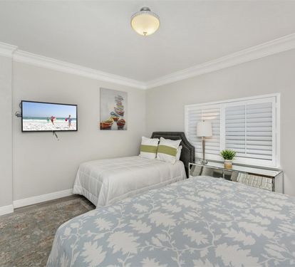 Your peaceful twin bedroom retreat features comfortable beds, wall-mounted TV, and elegant coastal artwork to help you unwind.