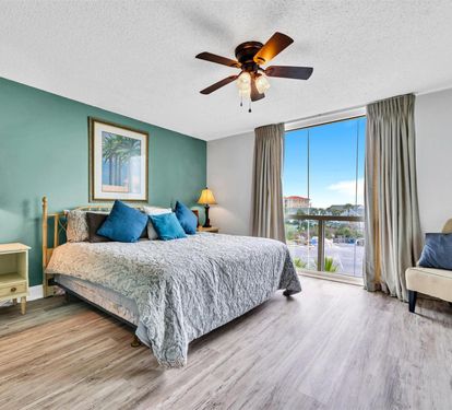 Sink into plush bedding and coastal charm in your spacious bedroom, where morning light reveals beautiful city views through floor-to-ceiling windows.