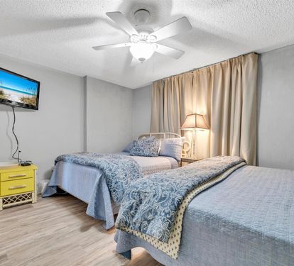 Unwind in your peaceful bedroom with dual beds, wall-mounted TV for evening entertainment, and gentle ceiling fan for comfort.