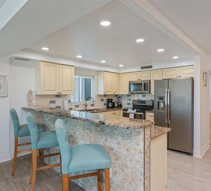 Your fully equipped kitchen awaits with granite counters, stainless appliances, and breakfast bar seating for casual coastal dining.