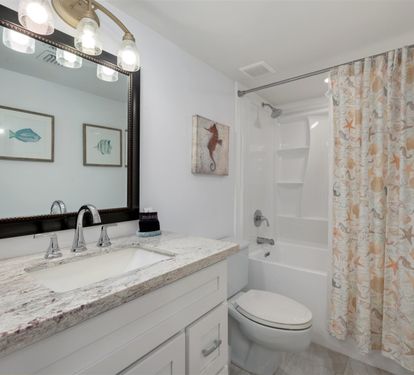 Step into your coastal-themed bathroom with marble counters, nautical artwork, and a relaxing tub-shower combo perfect for unwinding.