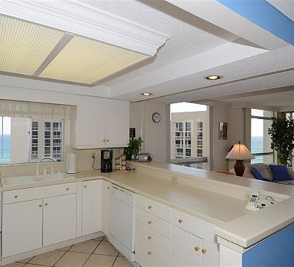 Your fully equipped kitchen awaits with pristine white cabinetry, spacious countertops, and stunning ocean views through charming glass-front cabinets.