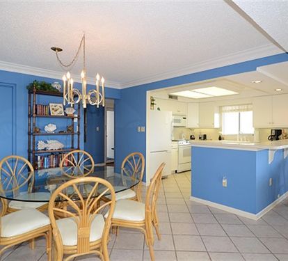 Bright coastal dining flows into your fully equipped kitchen, where cheerful blue walls and tropical furnishings create the perfect vacation atmosphere.