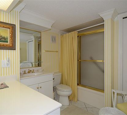 Your bright, cheerful bathroom features sunny yellow stripes and a deep soaking tub for relaxing after beach days.